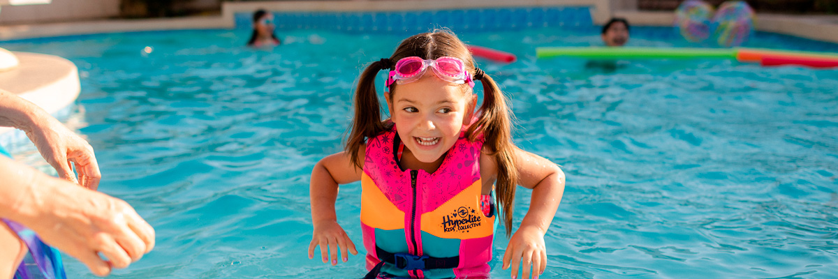 An image of a child wearing an approved life jacket in the pool.